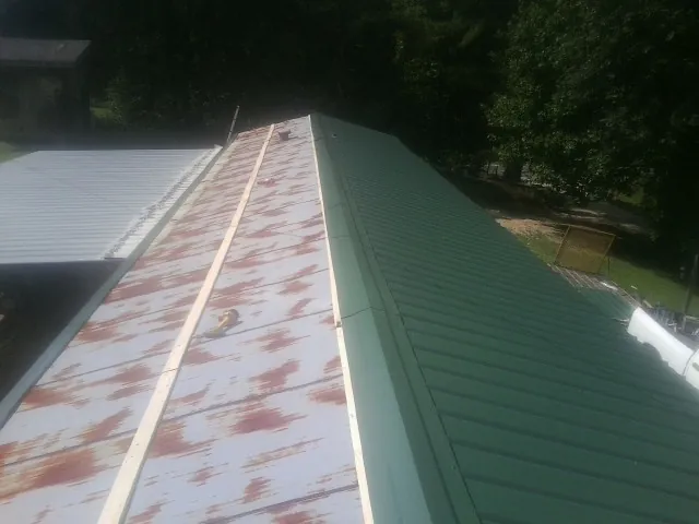 Old rusted panels beside newly installed green metal roofing — Wind Damage Roof Repair by Roofing Brothers in Christiansburg