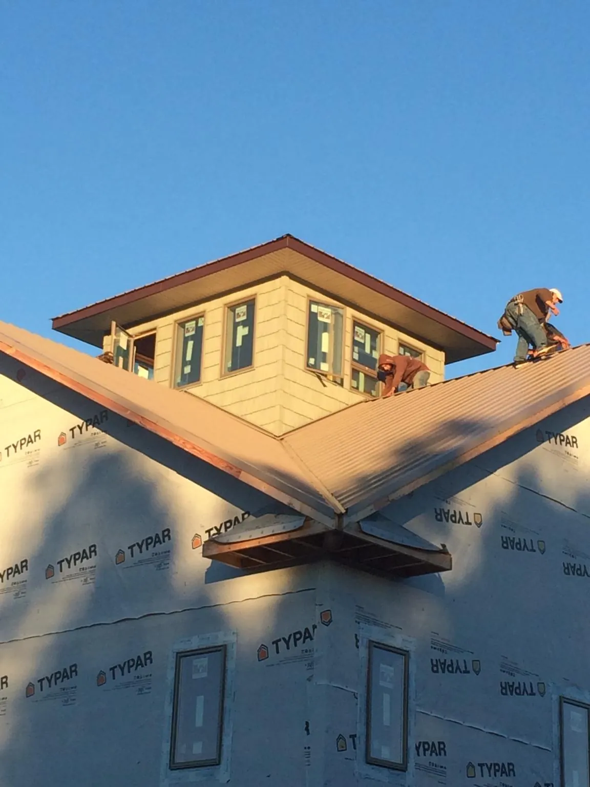 Roofers working around a rooftop cupola on a new metal roof at sunset — Roof Waterproofing in Christiansburg by Roofing Brothers